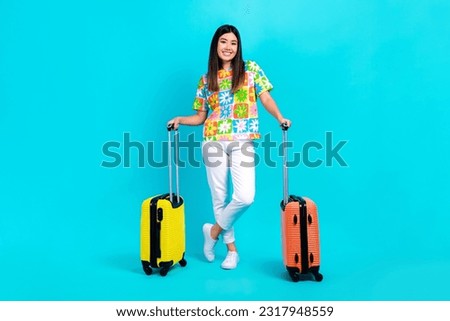 Full length photo of cute pretty lady wear flower print t-shirt holding luggage going flight check in isolated blue color background
