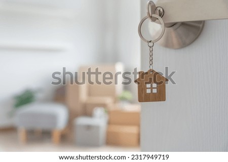 Moving house, relocation. The key was inserted into the door of the new house, inside the room was a cardboard box containing personal belongings and furniture. move in the apartment or condominium Royalty-Free Stock Photo #2317949719
