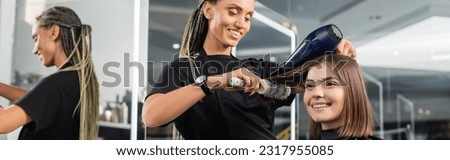 beauty salon, professional beauty worker with round brush and hair dryer styling hair of happy customer, brunette woman with short hair, salon blow dry, client satisfaction, hair volume, banner Royalty-Free Stock Photo #2317955085