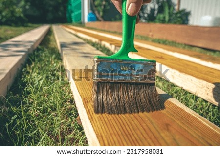 coating wooden boards with an antiseptic with a brush. construction, protective from humidity and mold Royalty-Free Stock Photo #2317958031