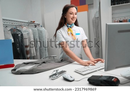 Laundry administrator checking information about clients garment on computer