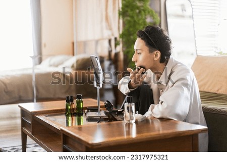 A young man is doing make-up in his room. applying foundation Royalty-Free Stock Photo #2317975321