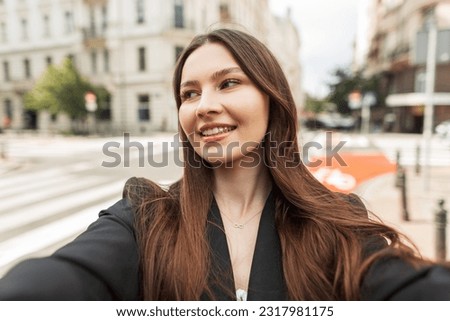 Happy beautiful fresh young girl model with smile in trendy fashion clothes taking selfie photo and walking in the city