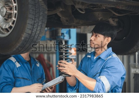Two professional car mechanics helping to repair shock absorbers and car suspension, all kinds of car experts, expert auto repair and accredited auto repair center. Royalty-Free Stock Photo #2317983865