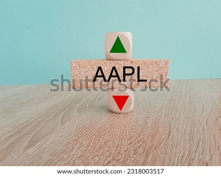 AAPL price symbol. A brick block with arrow symbolizing that AAPL index price are going down or up. Beautiful wooden table blue background. Business and gold price concept. Copy space.