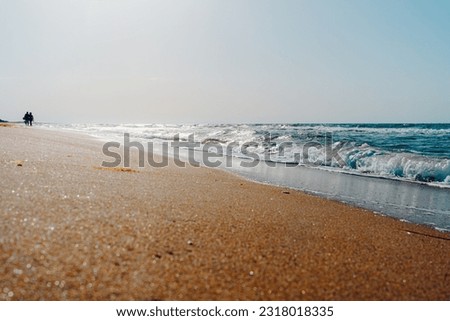 Silhouette of a couple walking along the sea coast or ocean coast. Waves on the sand. Summer vacation travel concept