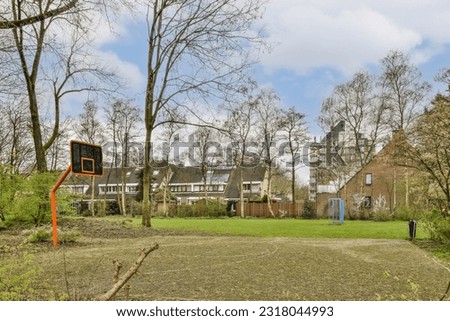 an outdoor basketball court in the middle of a residential area with trees and houses in the background on a cloudy day