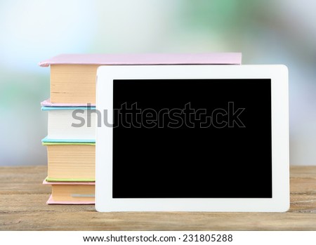 PC tablet and books on wooden table, on light background