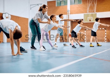 Schoolgirl and her classmates exercising with their sports teacher during physical education class. Royalty-Free Stock Photo #2318065939