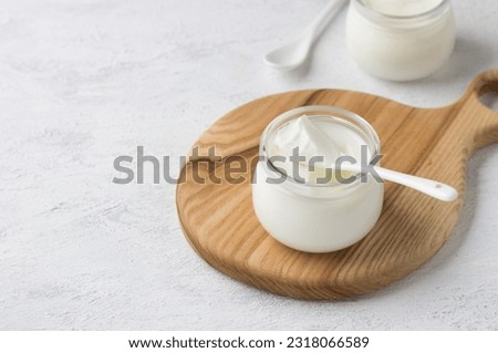 Natural homemade yogurt in a glass jar on a wooden board on a light gray background Royalty-Free Stock Photo #2318066589
