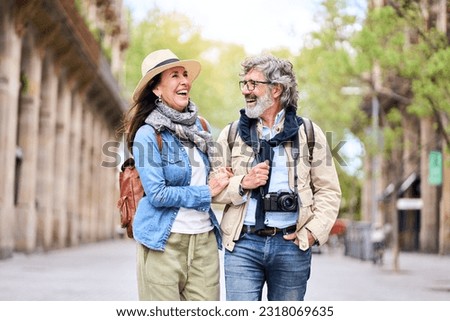 Happy older couple having fun walking outdoors in city. Retired people enjoying a sightseeing walk on street in spring. Mature couple relationships and vacations of pensioners. Royalty-Free Stock Photo #2318069635