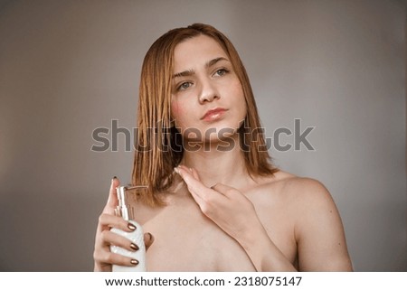 Portrait of a beautiful girl holds a jar of moisturizing body cream in her hand and applies it Skin care and beauty concept. Photo of attractive woman with natural make-up isolated on brown background