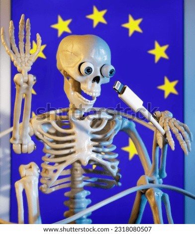 Skeleton toy holding a USB lightning cable He symbolize this connector death. Concept of the picture is depict the long-awaited decision of the EU in 2024 to enter common charger for mobile devices.