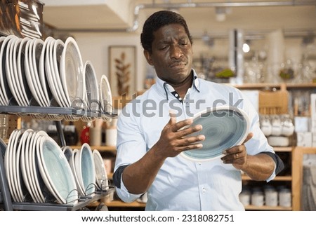 Focused african american man visiting household goods store in search of dishware.. Royalty-Free Stock Photo #2318082751