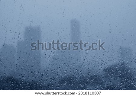 Rain drop on glass window in monsoon season with blurred city buildings background. Royalty-Free Stock Photo #2318110307