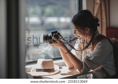 Beautiful girl takes picture of landscape with her smartphone sitting on train..
