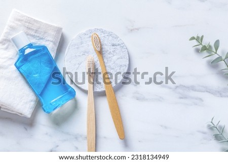 Bamboo toothbrush with mouthwash and towel on marble background, dental care and oral hygiene, top view Royalty-Free Stock Photo #2318134949