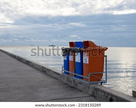 Waste sorting. Separate waste collection bins at seaside with a boat and sky background. Inscriptions in English and Thai: metal, plastic, paper, mixed waste