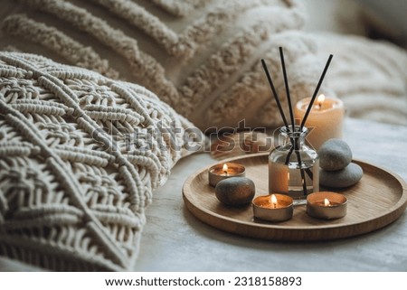 Apartment natural aroma diffusor with sea breeze fragrance. Burning candles on bamboo tray, cozy home atmosphere. Relaxation, detention zone in the living or bedroom. Stones as decor Royalty-Free Stock Photo #2318158893