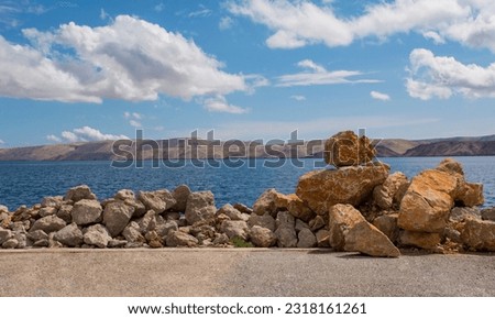 Rocks on the Adriatic coast of Croatia in the town of Karlobag in Lika-Senj county, late spring. Looking towards Otok Pag island Royalty-Free Stock Photo #2318161261