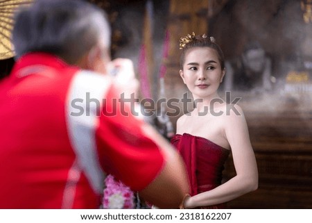 back view of photographer taking photo of model in Thai dress costume traditional according Thai culture in ancient Thai house, Girl from behind photographing indoors