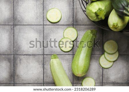 Fresh cut and whole zucchini on black tile background