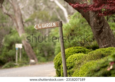 wooden garden sign saying to garden, next to a path in a forest In Australia 