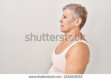 Middle age caucasian woman standing over white background looking to side, relax profile pose with natural face with confident smile. 