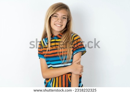 beautiful caucasian teen girl wearing striped sweater over white studio wall laughing.