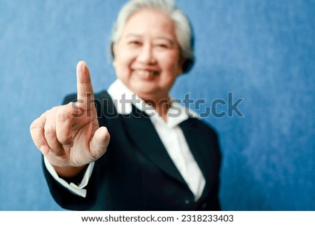 An elderly Asian businesswoman puts her right index finger forward. Modern business concepts. Senior executives. copy space