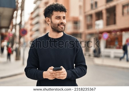 Young arab man smiling confident using smartphone at street Royalty-Free Stock Photo #2318235367