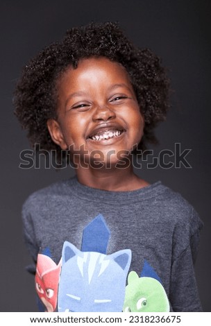Captivating studio portrait of a young Ethiopian girl radiating pure joy, as she indulges in playful silliness and showcases her delightful expressions on a black seamless backdrop.