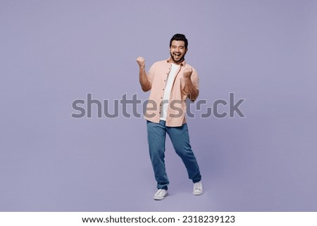 Full body young Indian man he wear pink shirt white t-shirt casual clothes doing winner gesture celebrate clenching fists say yes isolated on plain pastel light purple background. Lifestyle concept Royalty-Free Stock Photo #2318239123