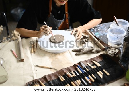 Young sculptor creating handmade ceramic plate on the pottery wheel in workshop. Indoors lifestyle activity, handicraft, hobbies concept