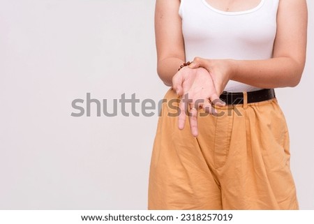 A close up image of a tan woman in a white sleeveless blouse massaging her wrist. Dealing with Carpal Tunnel Syndrome. Isolated on a white background.
