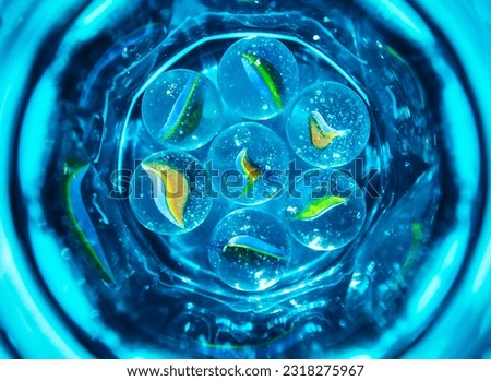 abstract photo with colorful glass balls in blue glass with water, fantastic background