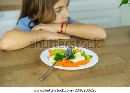The child eats vegetables on a chair. Selective focus. Kid.