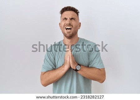Hispanic man with beard standing over white background begging and praying with hands together with hope expression on face very emotional and worried. begging.  Royalty-Free Stock Photo #2318282127