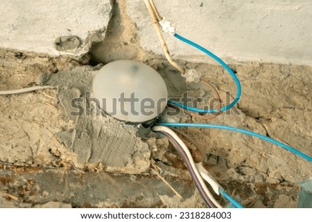 Wires under the ceiling. An old ball with wiring on the wall. The wiring was not done correctly. Old wires in the wiring are dangerous. Royalty-Free Stock Photo #2318284003