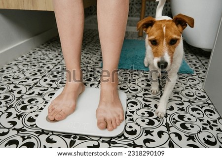 Bare feet woman checking her weight on weighing scales in bathroom. Female measuring her weight using digital scales on floor. Royalty-Free Stock Photo #2318290109