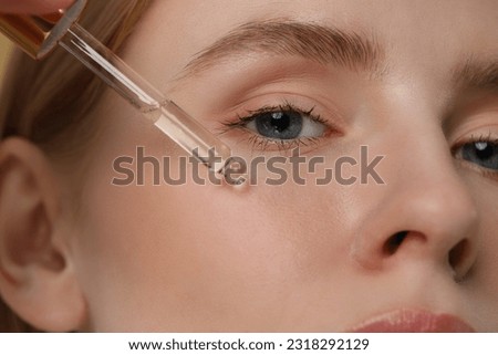 Woman applying essential oil onto face, closeup Royalty-Free Stock Photo #2318292129