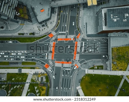 Beautiful aerial view of cars at a crossroads in Milan. Direct top view of the road traffic in the big city on a sunny evening.