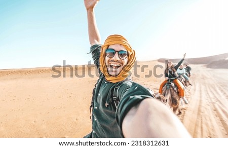 Happy tourist having fun enjoying group camel ride tour in the desert - Travel, life style, vacation activities and adventure concept Royalty-Free Stock Photo #2318312631