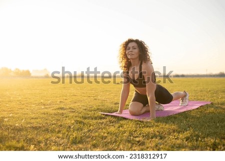 girl goes in for sports at sunset on the grass using a gymnastic mat.