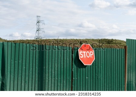 Green gate with stop signal. Power line in the background. High quality photo