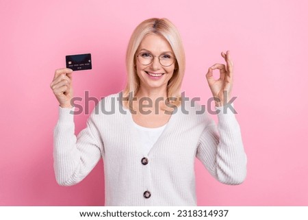 Photo of shiny confident woman dressed white cardigan eyewear showing okey rising credit card isolated pink color background