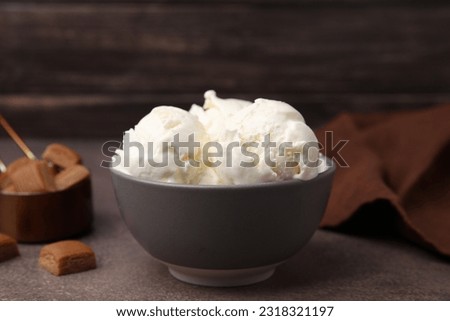 Delicious vanilla ice cream in bowl on textured table