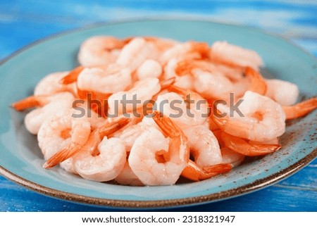 Fresh prawns. Raw shrimps, prawns in a plate on a blue background. Seafood. 
