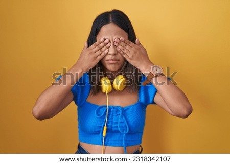 Hispanic young woman standing over yellow background rubbing eyes for fatigue and headache, sleepy and tired expression. vision problem 