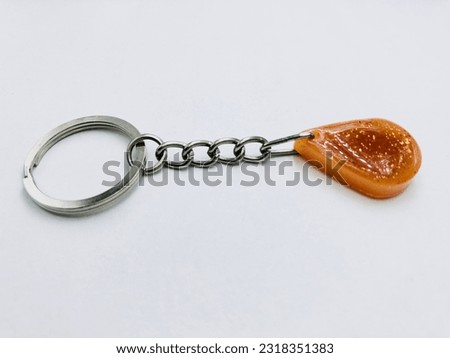 A orange colour, water drop shape keytag on white background.It has orange glitter powder and silver keychain. It made of resin material. This picture was taken from the side of the keytag. Beautiful.